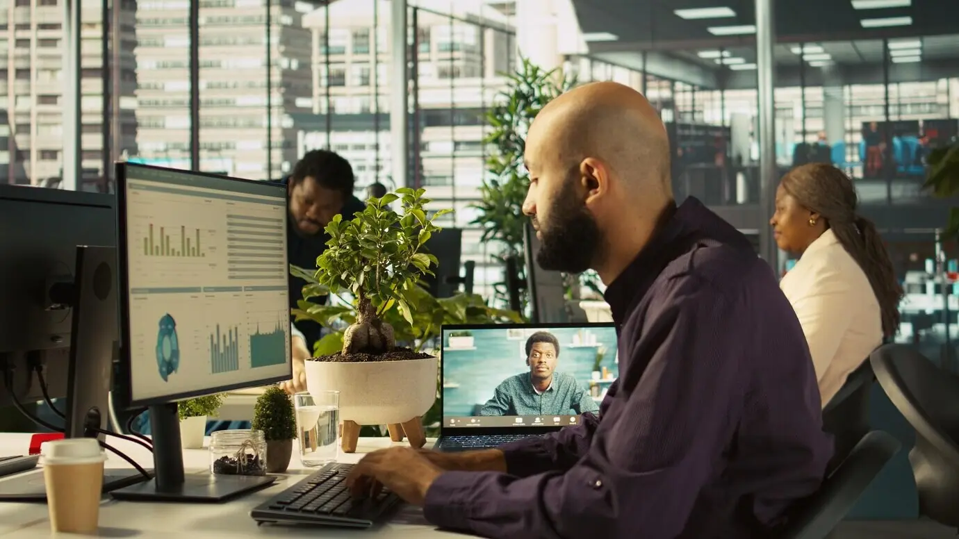 Бизнес-менеджер на видеозвонке с работником, присутствующим на встрече-брифинге.
